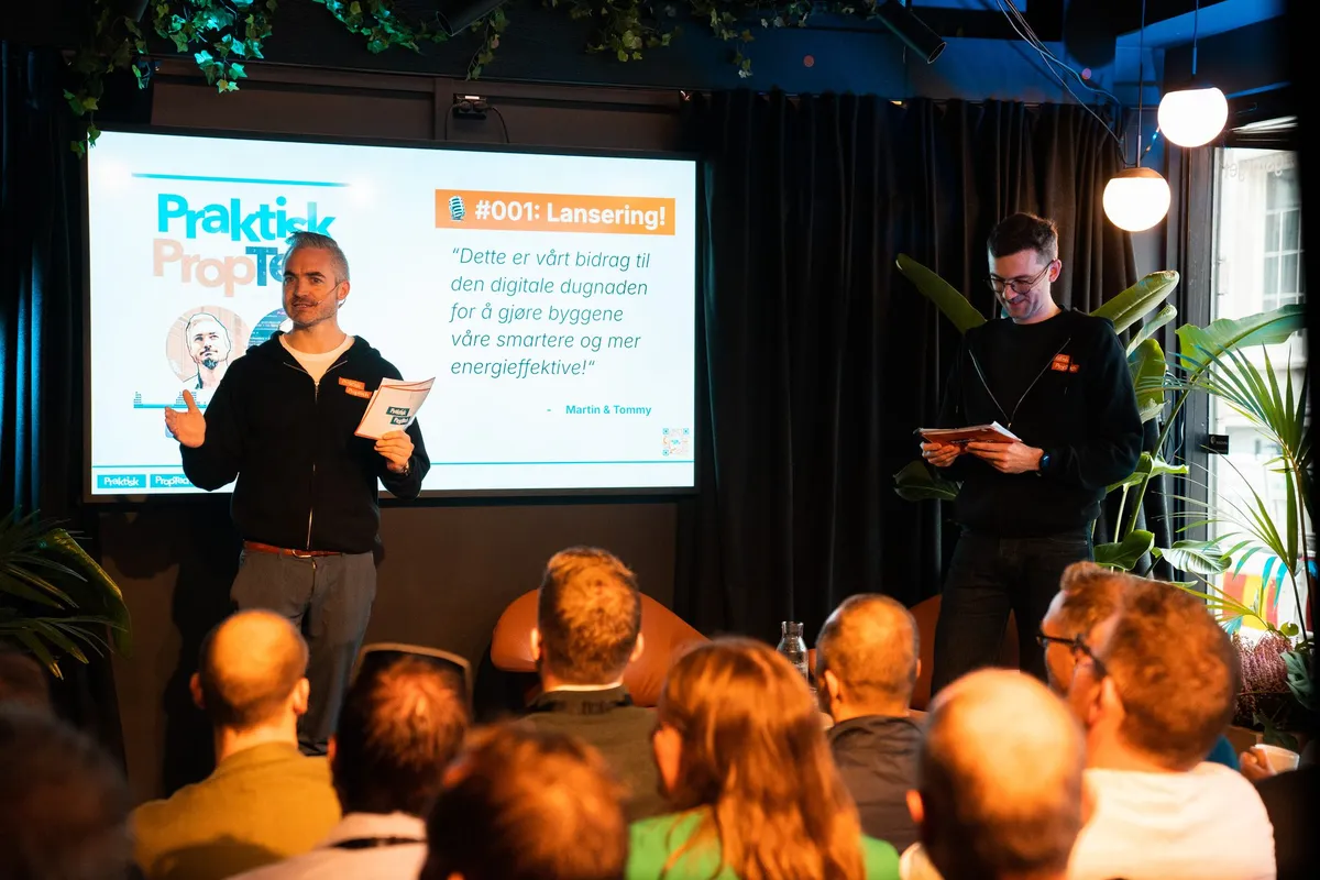 Tommy og Martin på scenen foran sliden «#001: Lansering!», med fullt publikum foran