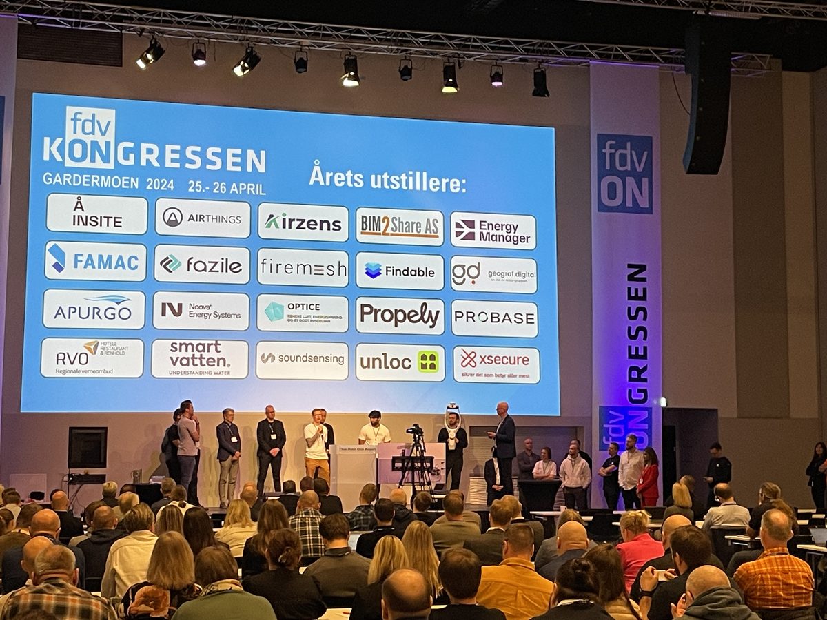 Storskjermen med FDVkongressens logo og årets utstillere over en full sal