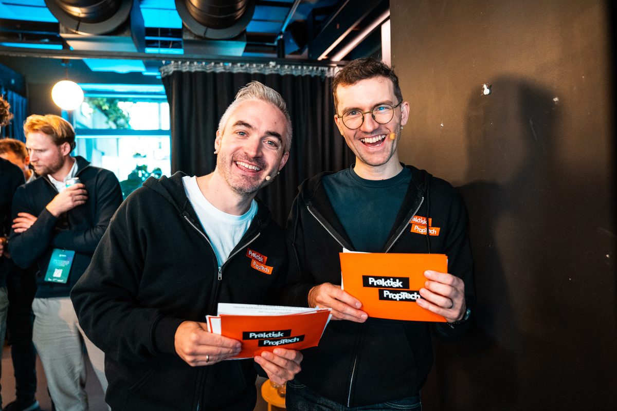 Martin og Tommy smiler med hvert sitt oransje Praktisk PropTech-kort