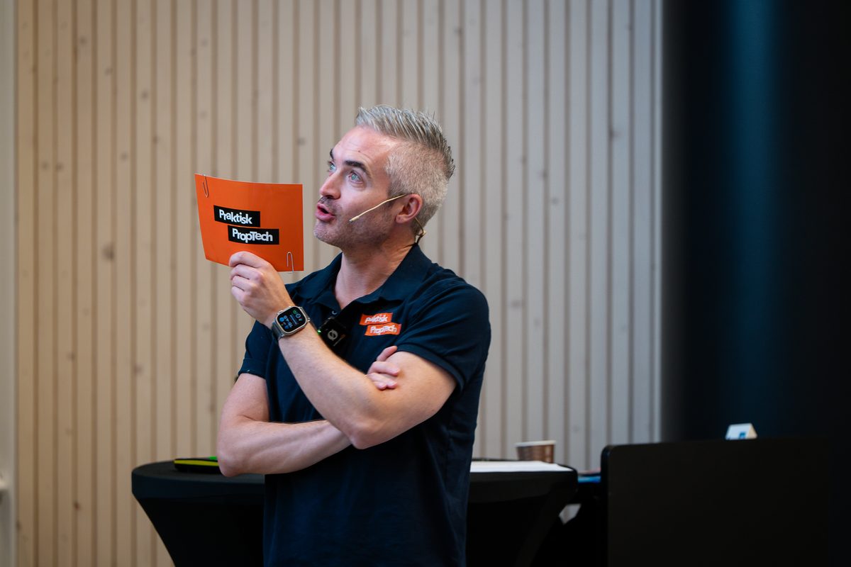 Tommy holder opp et oransje Praktisk PropTech-kort