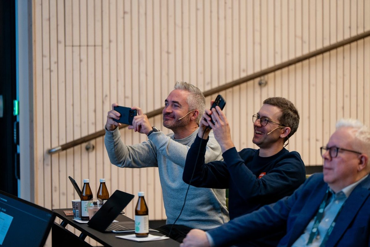 Tommy og Martin sitter på første rad og tar bilder med mobilen
